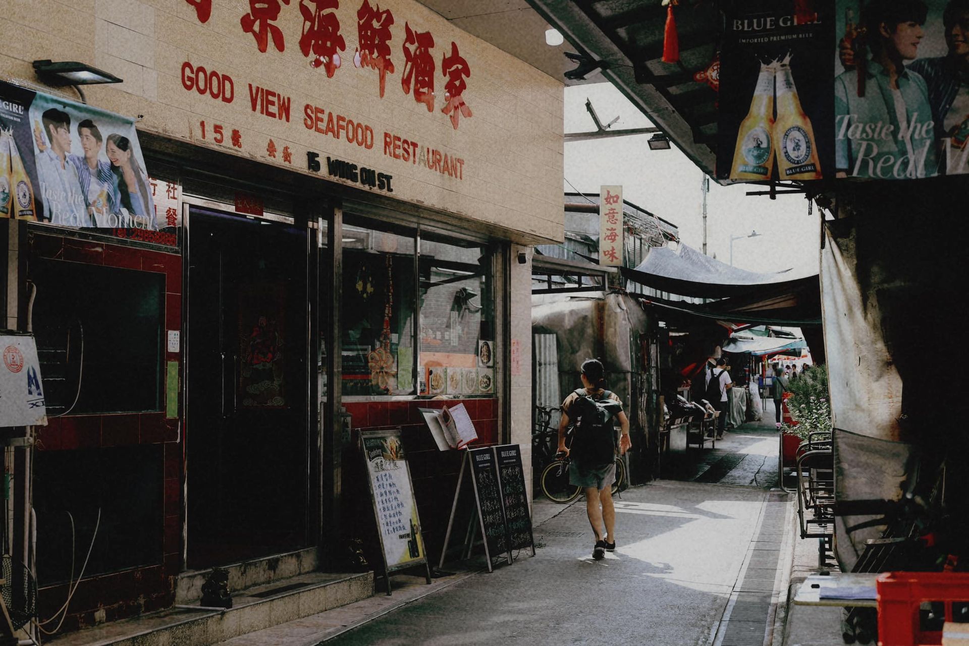 A man walking down a street in front of a building that says good new seafood