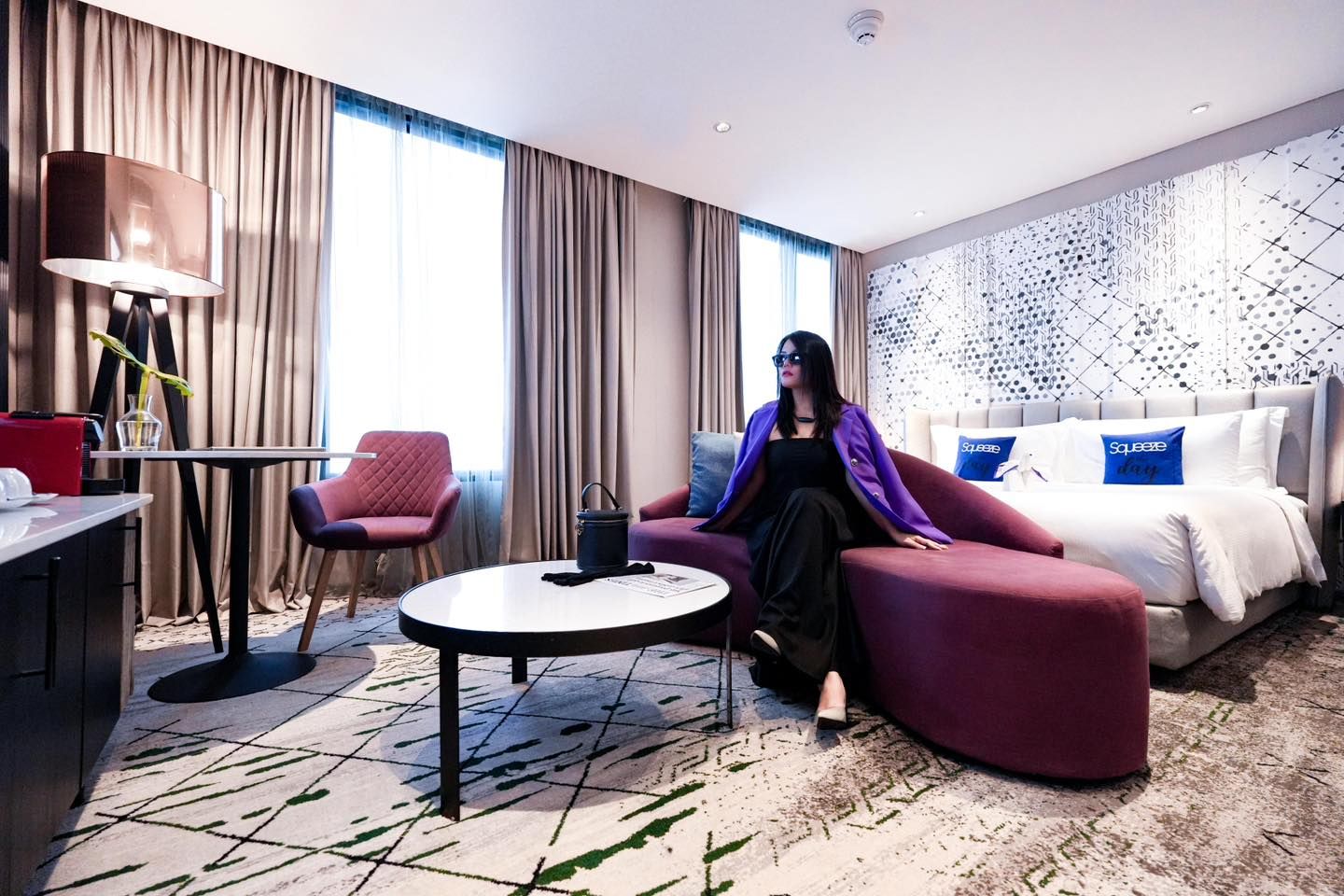 A woman is sitting on a couch in a Avani Sukhumvit hotel room.