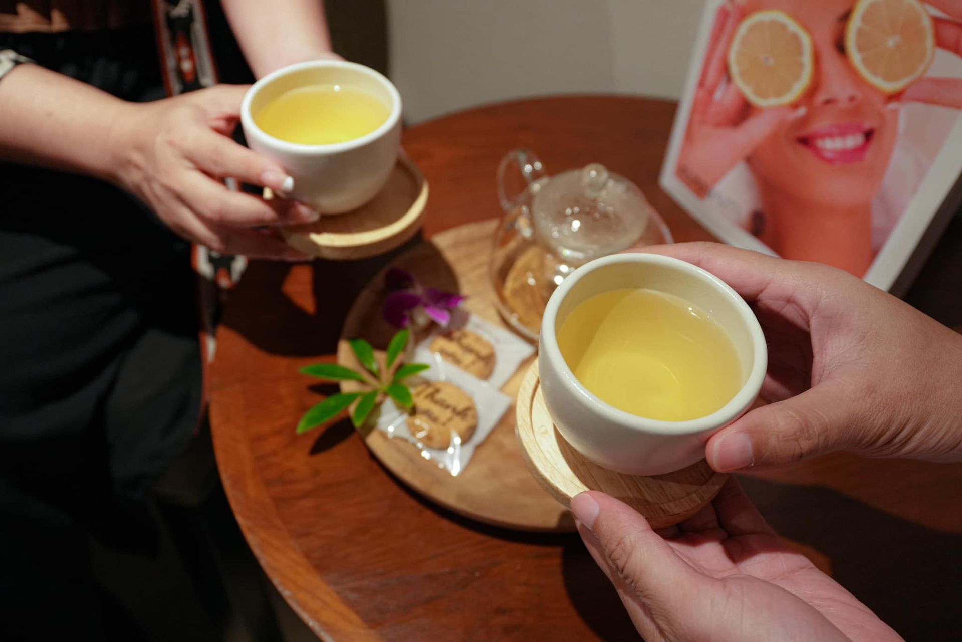 Two people are holding cups of tea on a table.