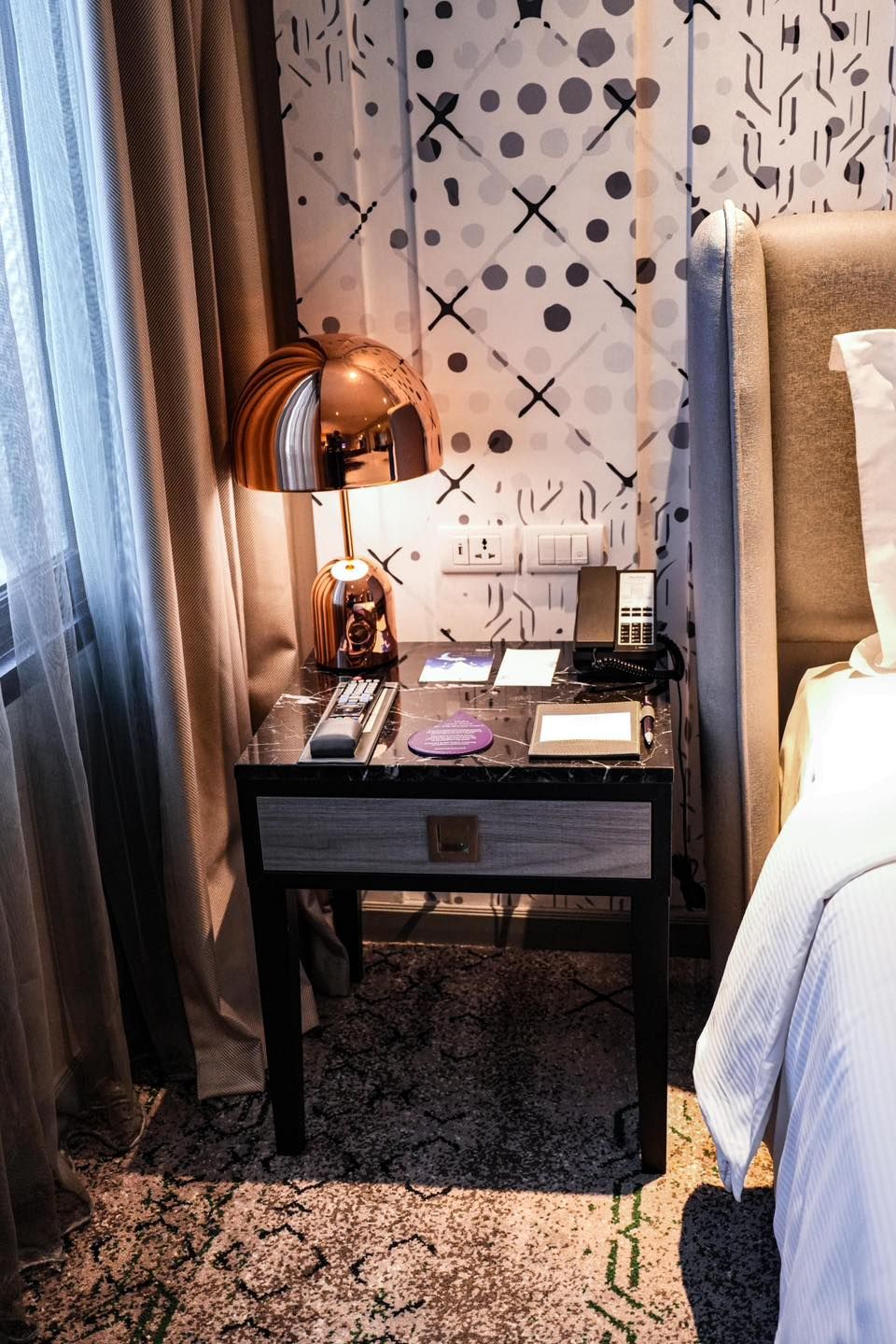 A bedroom with a bed and a nightstand with a lamp on it.