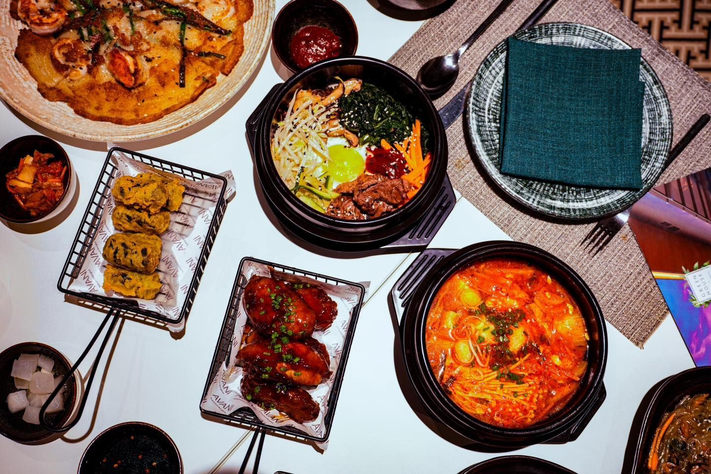 A table topped with plates of food and bowls of soup.