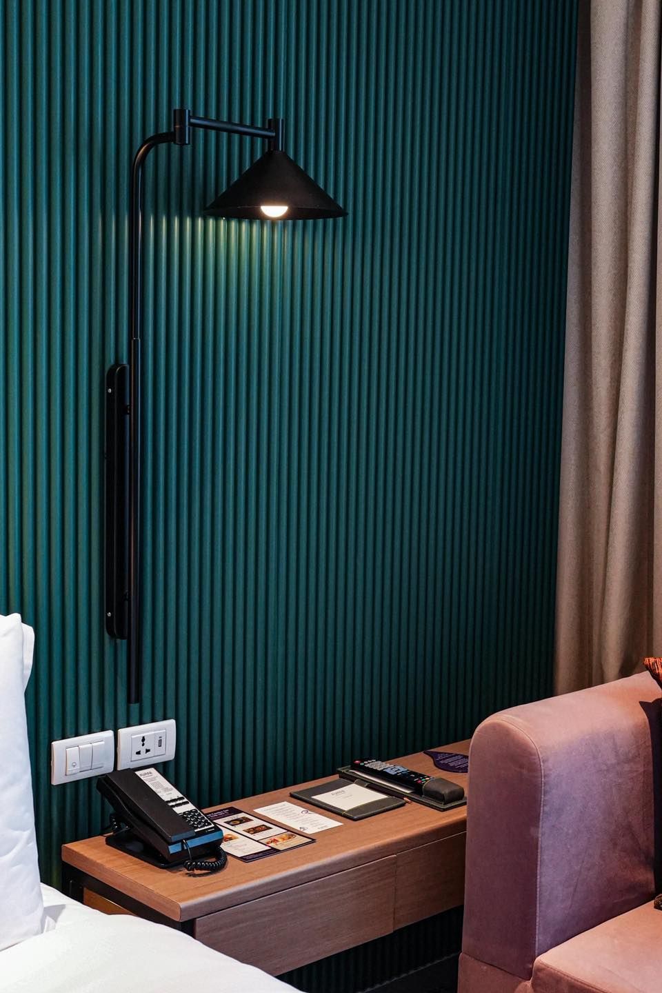 A hotel room with a bed , desk , lamp and telephone at Avani Sukhumvit Bangkok.