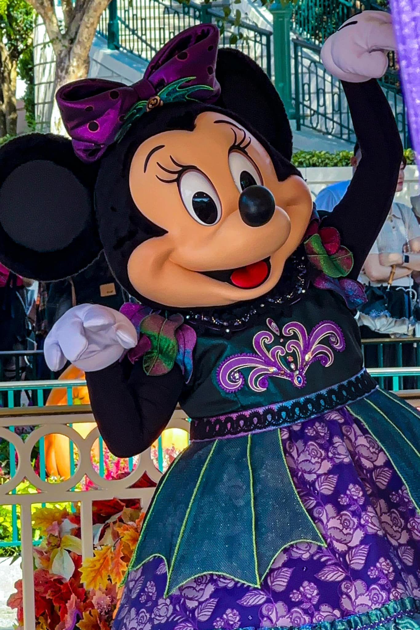 Minnie mouse is wearing a purple dress and holding a balloon.