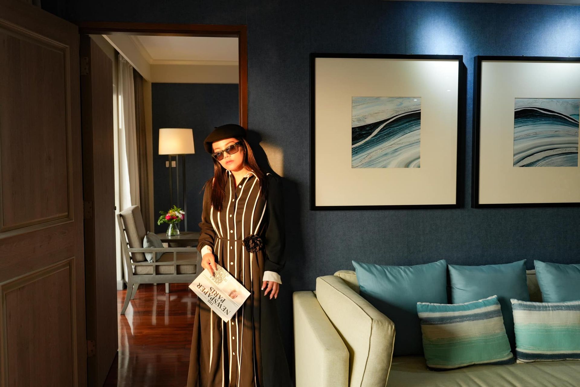 A woman in a striped dress is standing in a living room next to a couch.