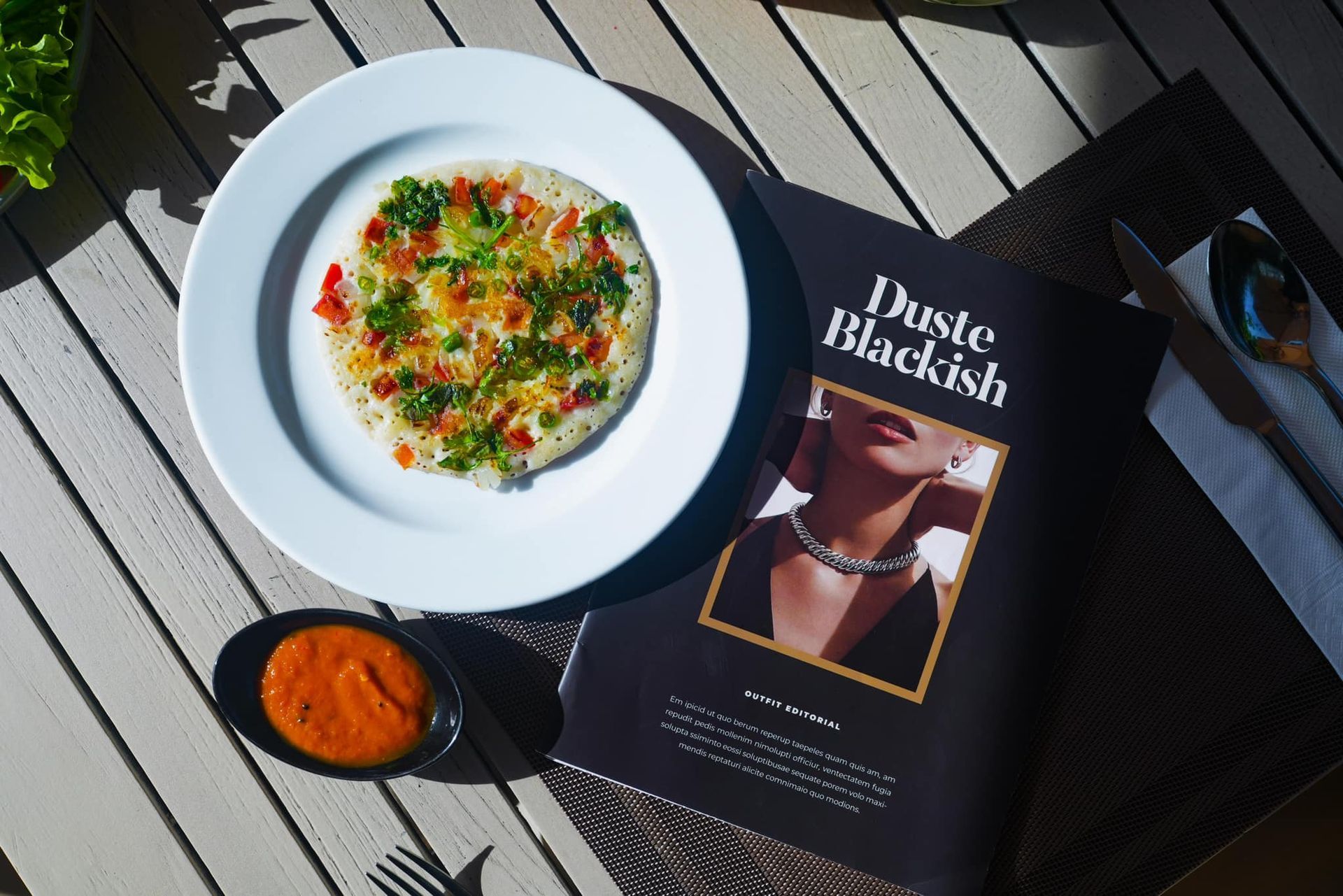 A plate of food next to a magazine that says dust blackish