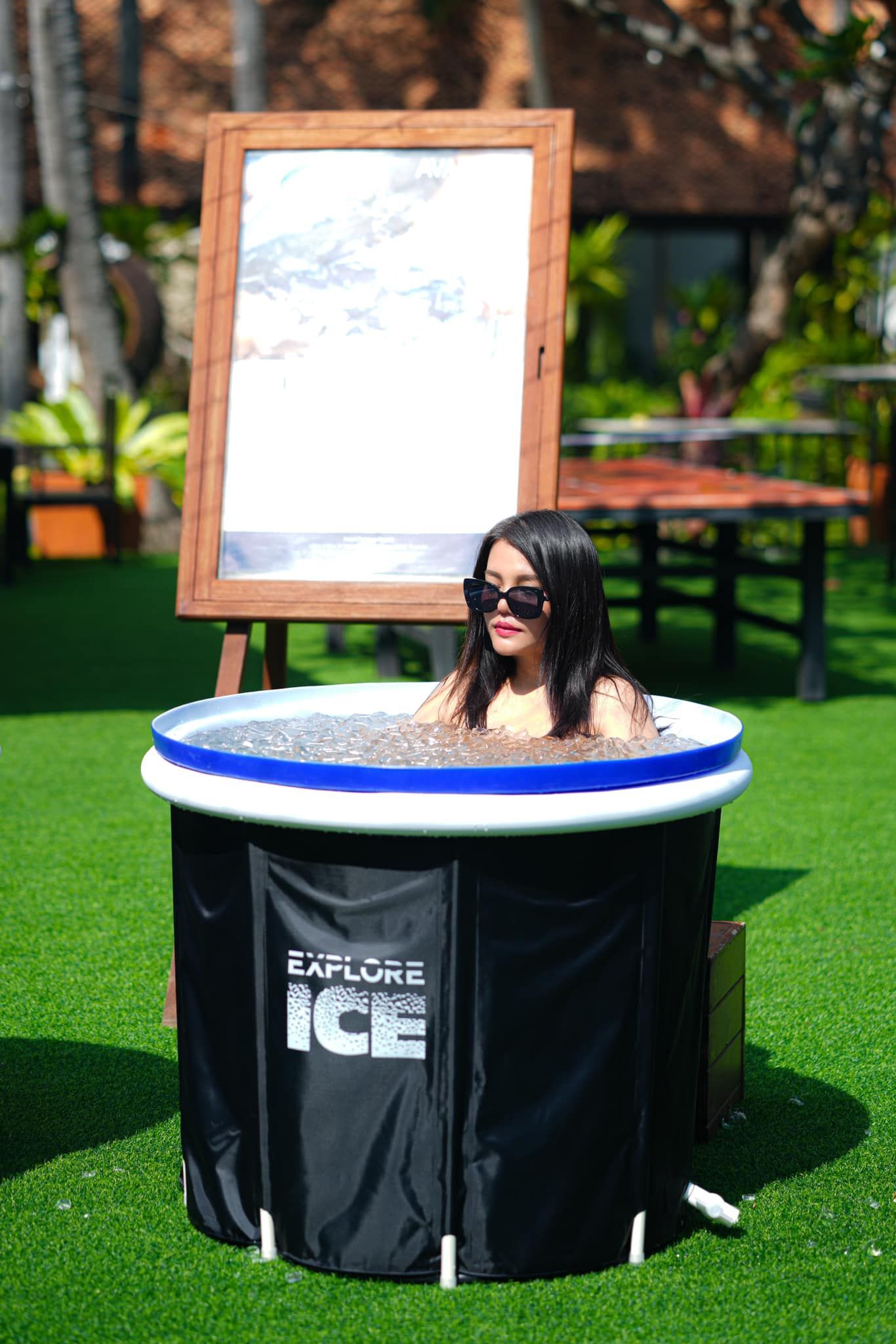 A woman is sitting in a tub of ice.