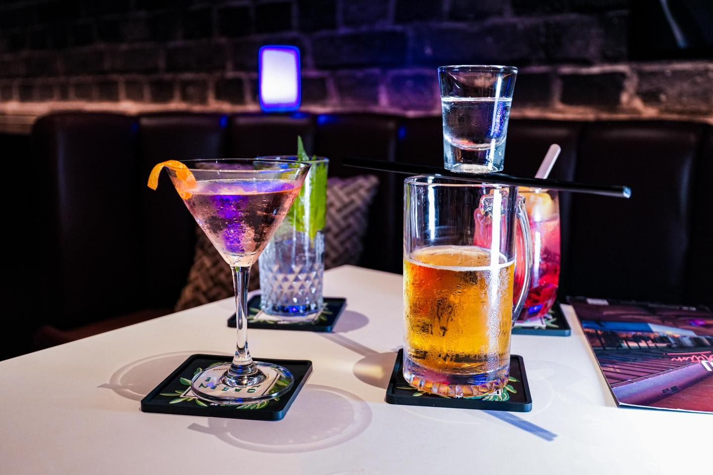 A table topped with a martini , a shot glass and a beer.