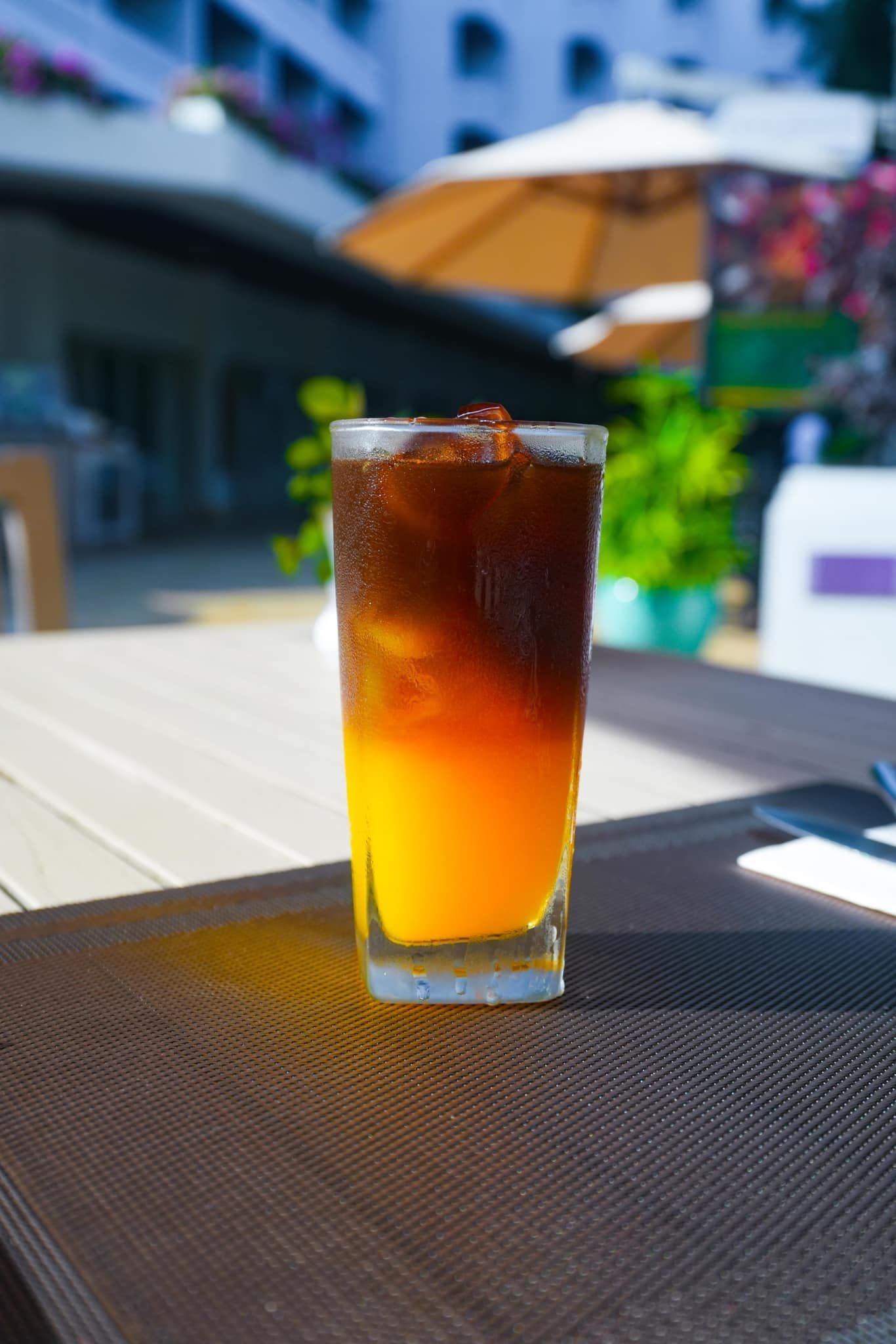 A glass of orange juice and iced coffee on a table.