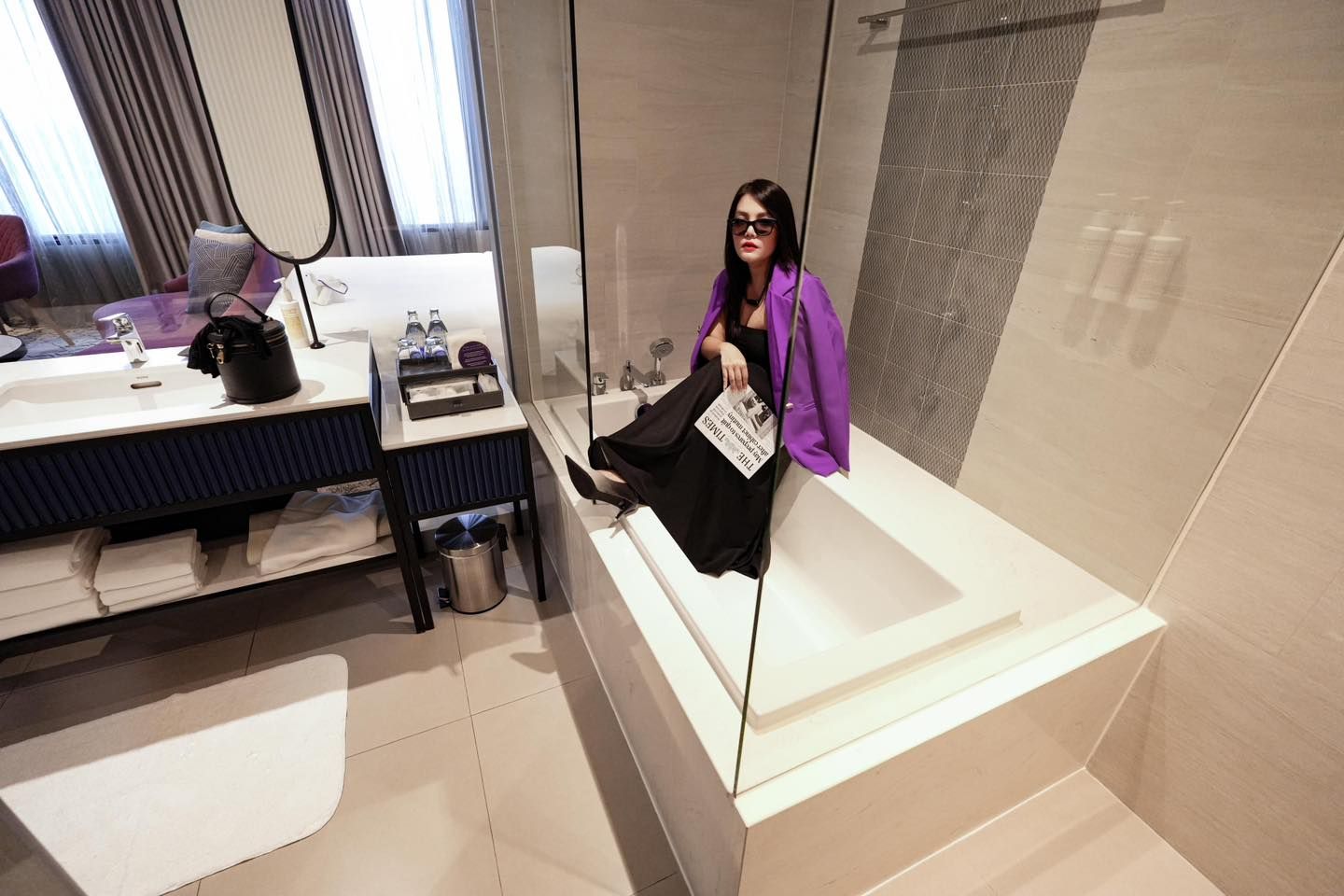 A woman is sitting on a bathtub in a bathroom in Avani Sukhumvit Bangkok hotel.
