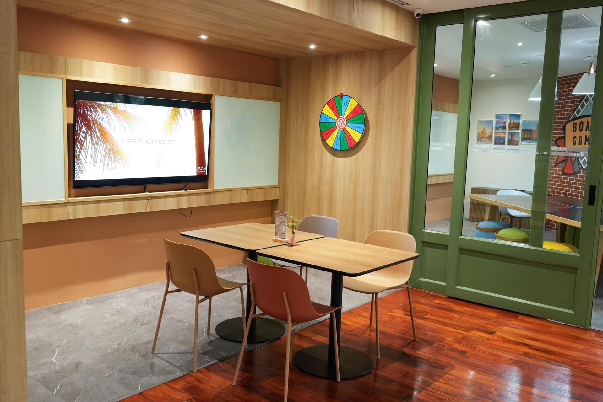 A room with a table and chairs and a television on the wall.