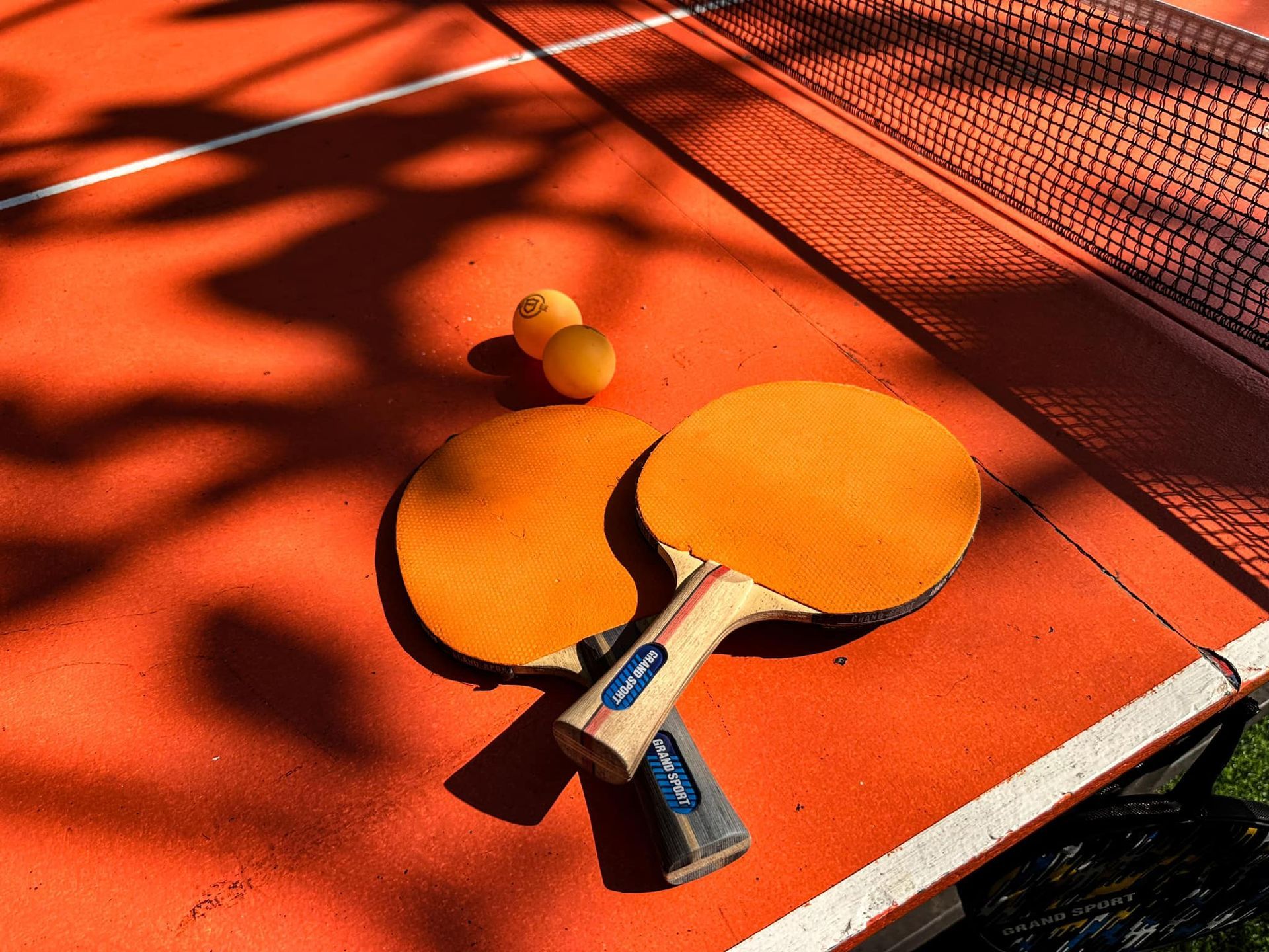 Two ping pong paddles and two balls on a table
