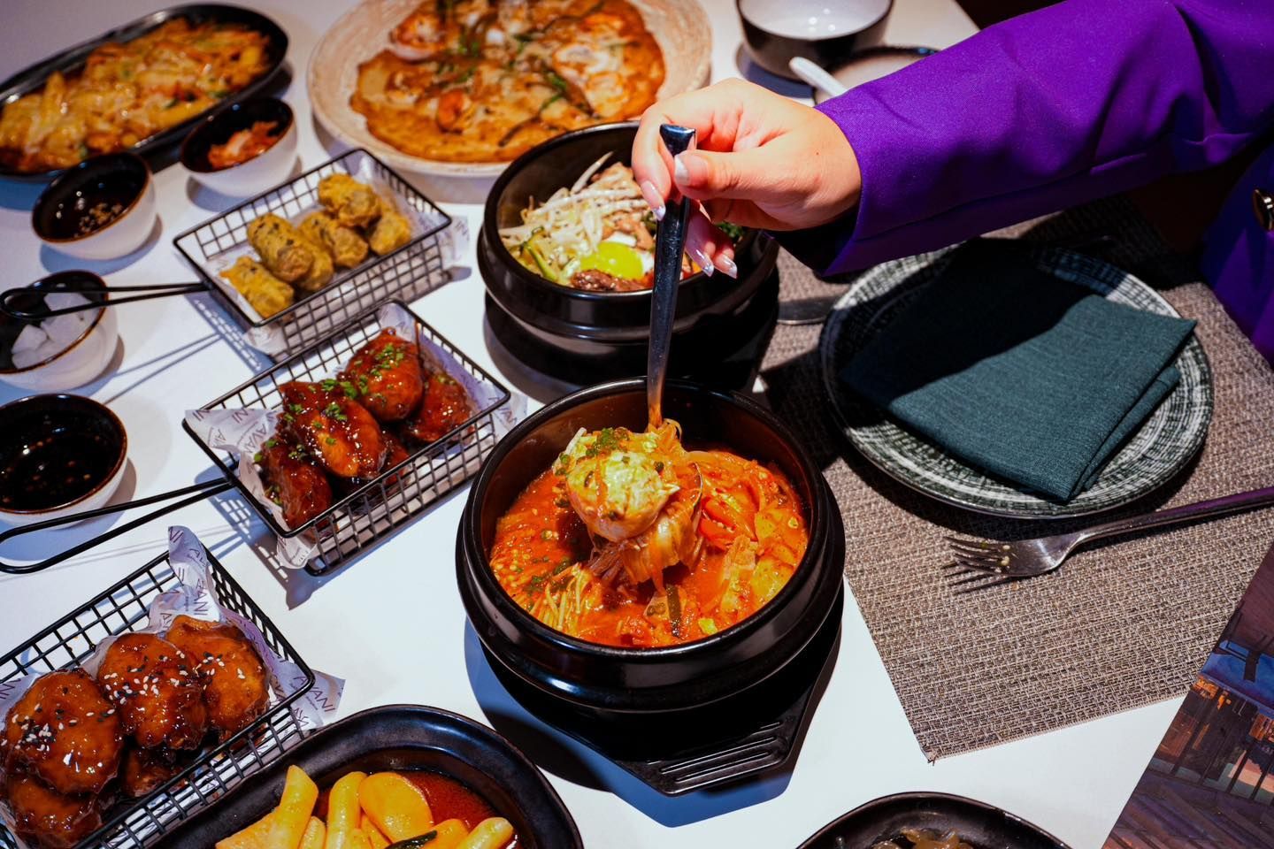 A person is holding a fork over a bowl of food on a table.