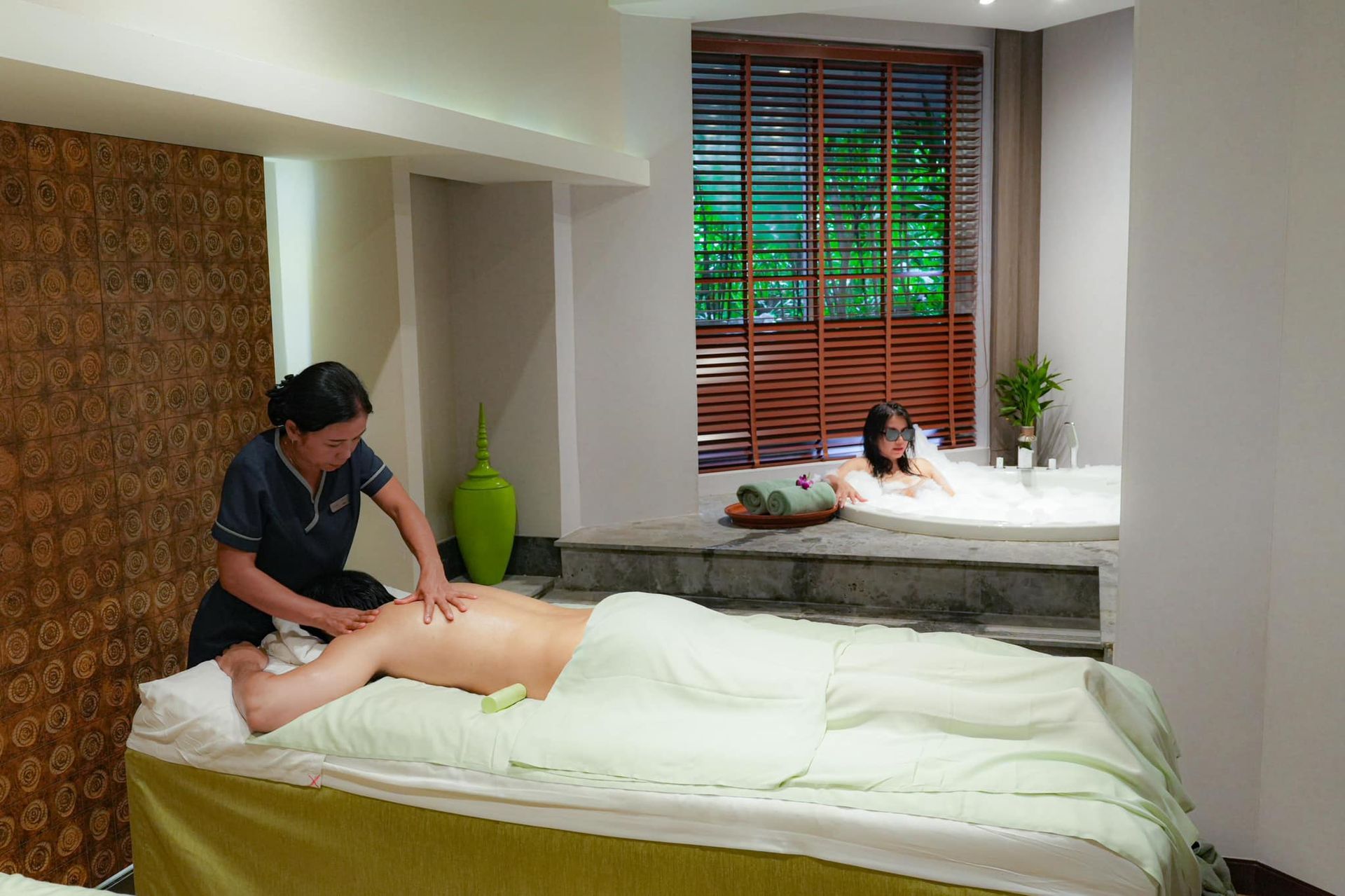 A woman is giving a man a massage in the Avani spa.
