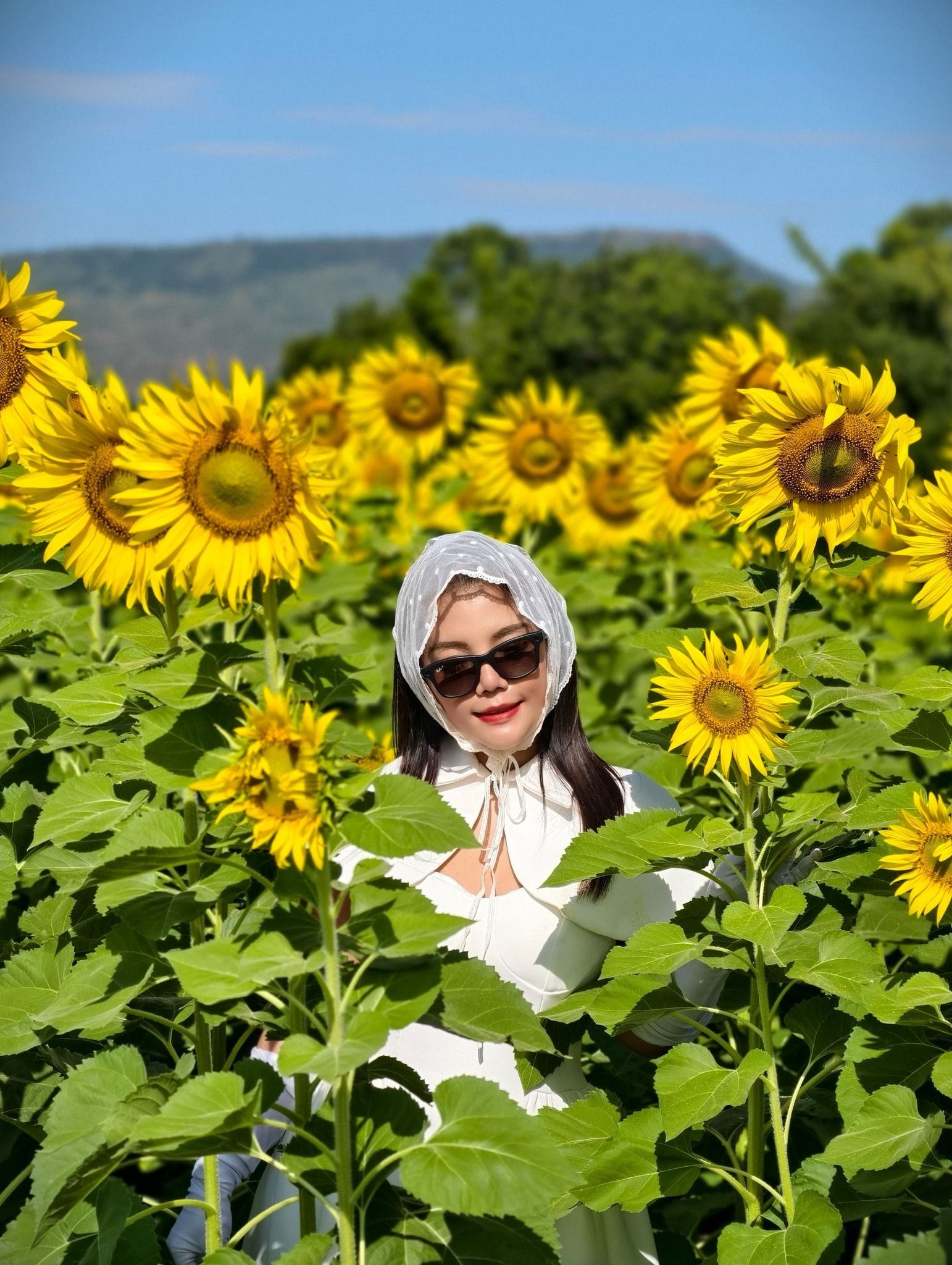 A woman is standing in a field of sunflowers.