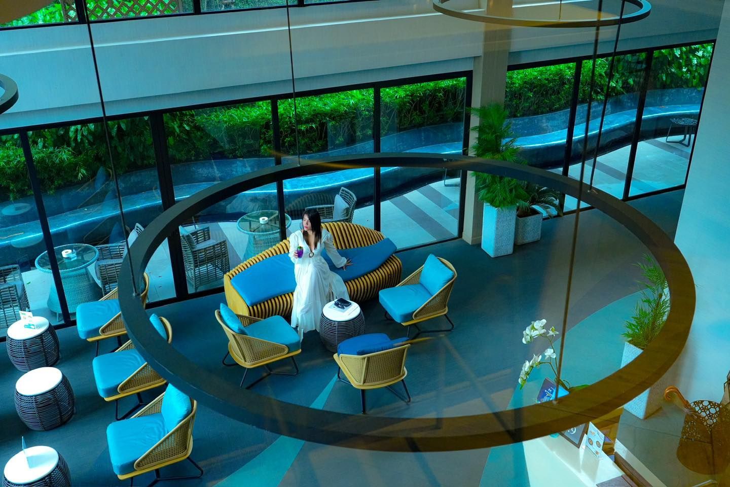 A woman in a white dress is standing in a room with a couch and chairs.