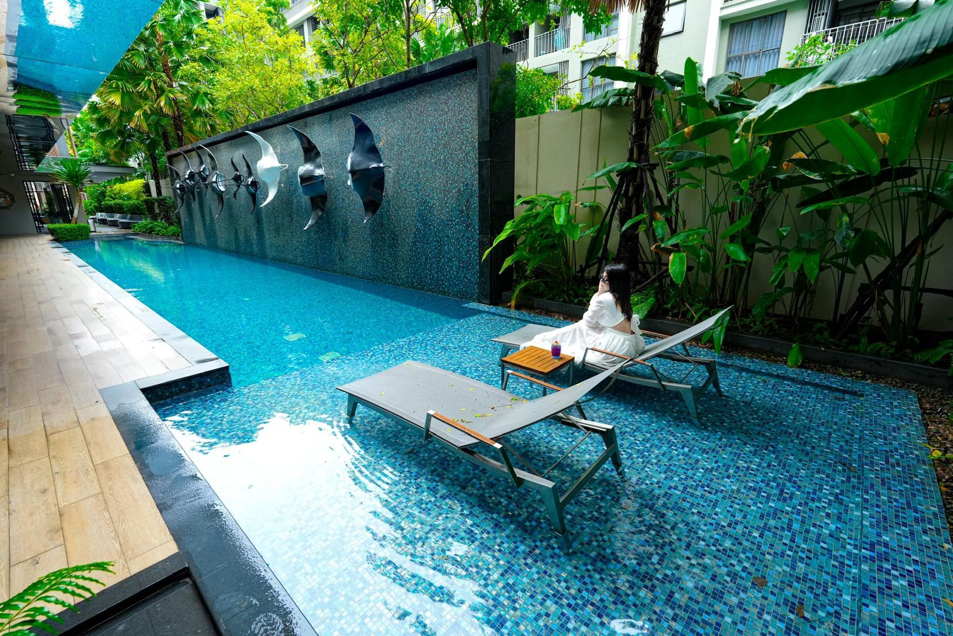 A woman is sitting on a lounge chair in a swimming pool.