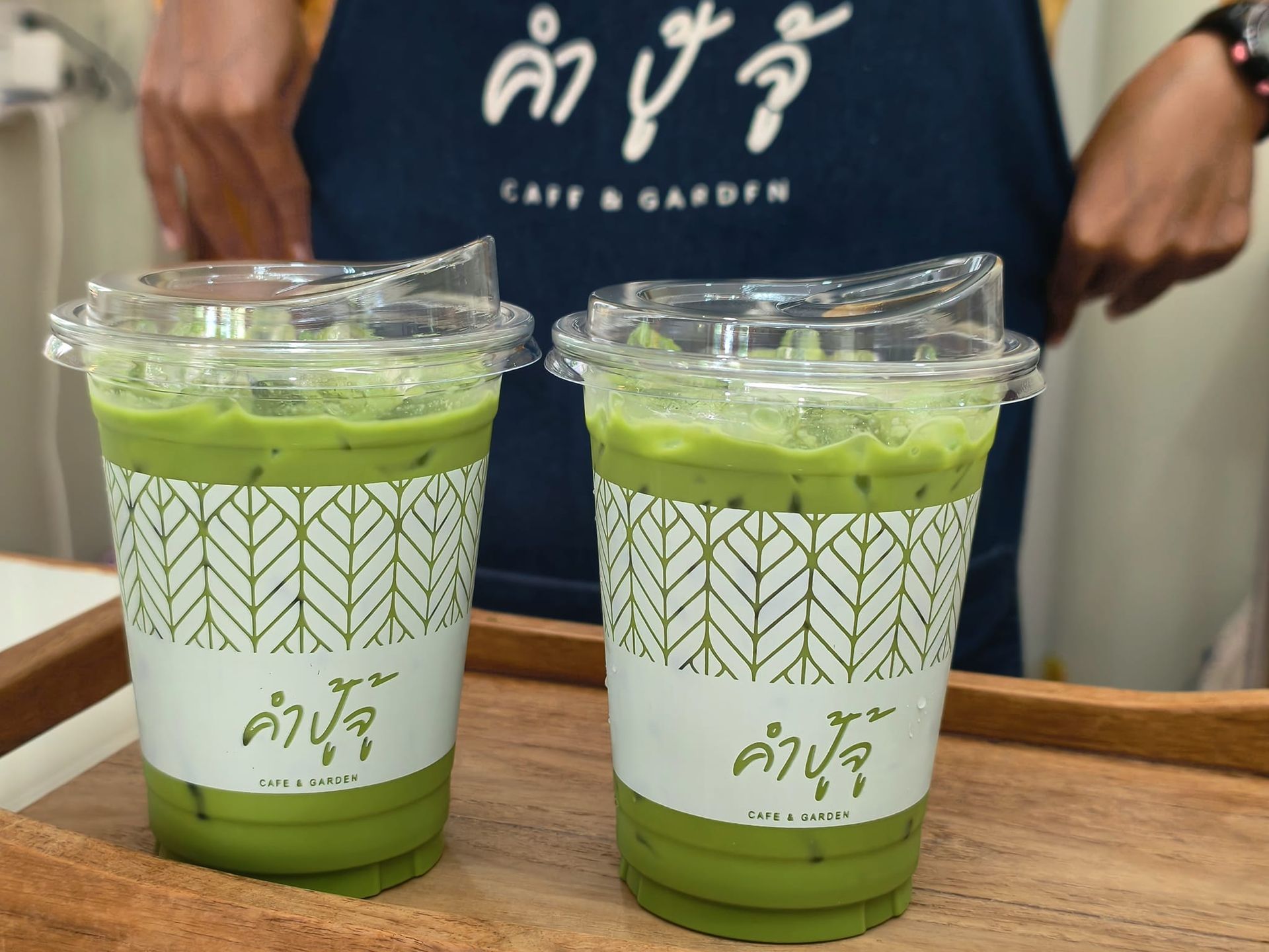 Two cups of green tea are sitting on a wooden tray.