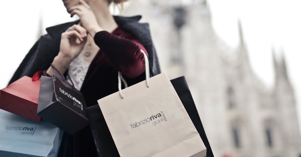 A woman is holding a bunch of shopping bags in front of a building.