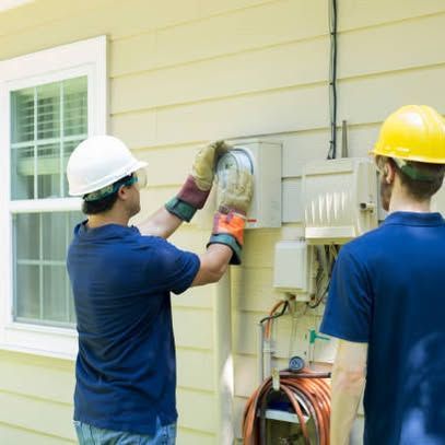 Two electricians in hard hats work on an outdoor electrical panel beside a house