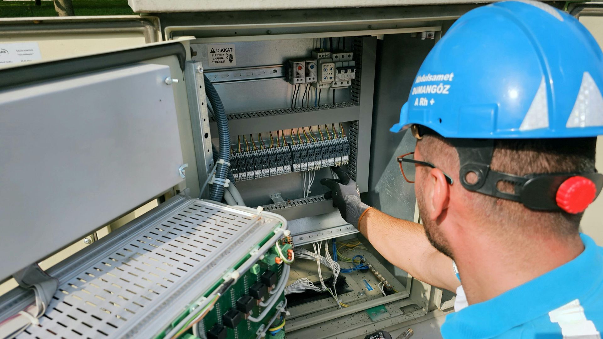 A man wearing a hard hat is working on a computer.