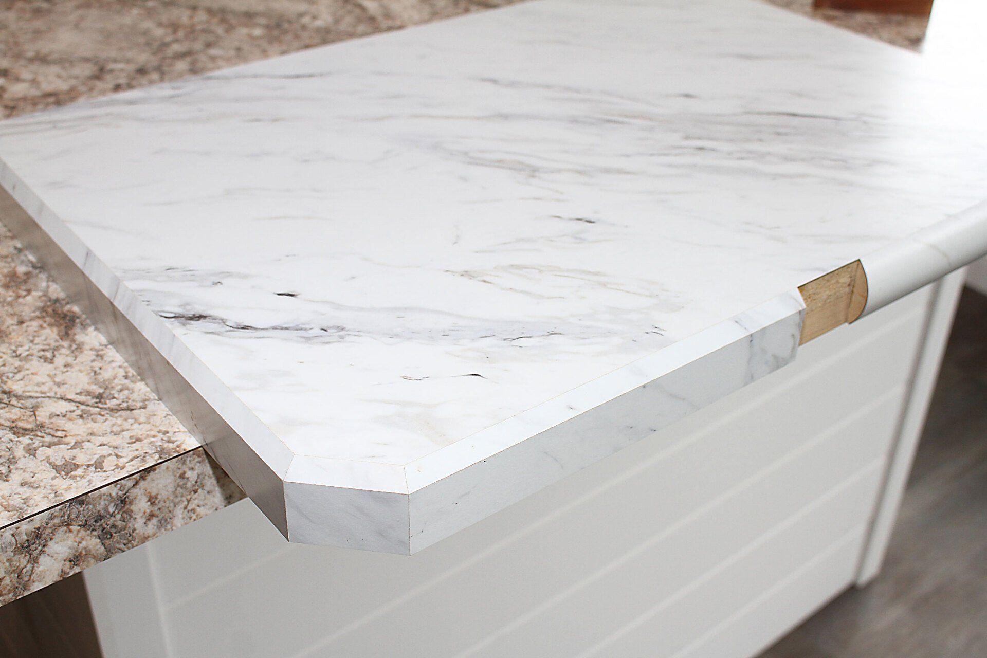 White marble-look countertop with a missing corner piece, set on a white cabinet.