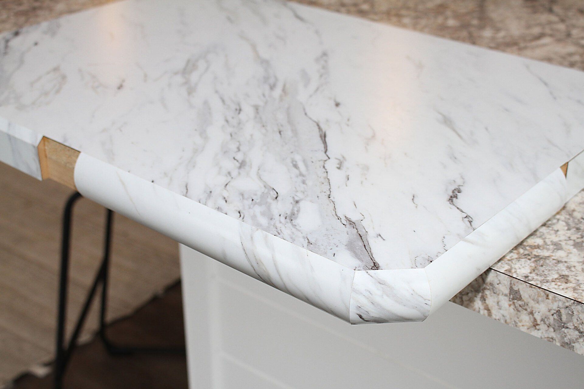 Close-up of a kitchen countertop with marble-like pattern and protective edging.