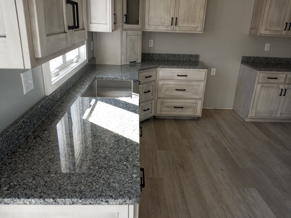 Kitchen with granite countertops, light-colored cabinets, and wood-look flooring.