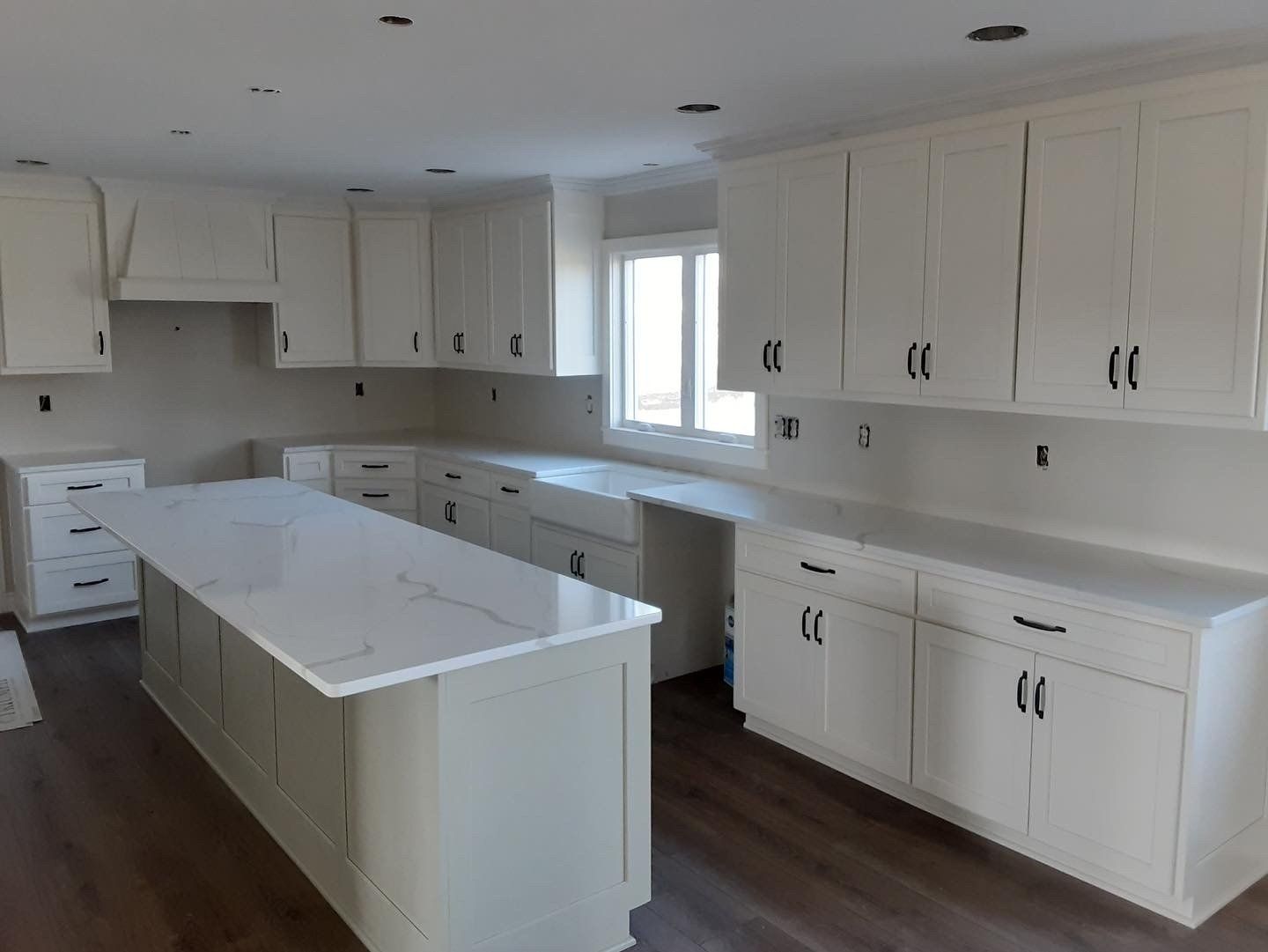White kitchen with island, cabinets, and countertops; dark hardware.