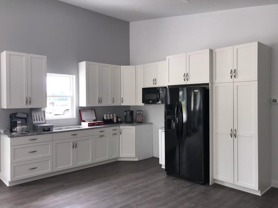 White kitchen cabinets with black appliances; gray walls and flooring.