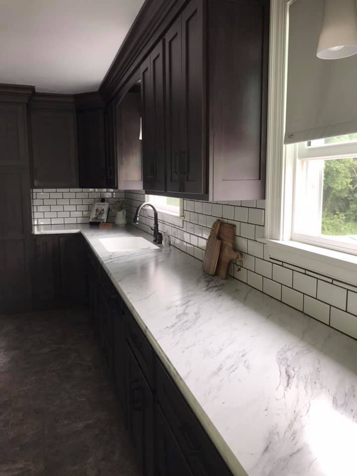 Dark gray kitchen cabinets with a white countertop and white subway tile backsplash.