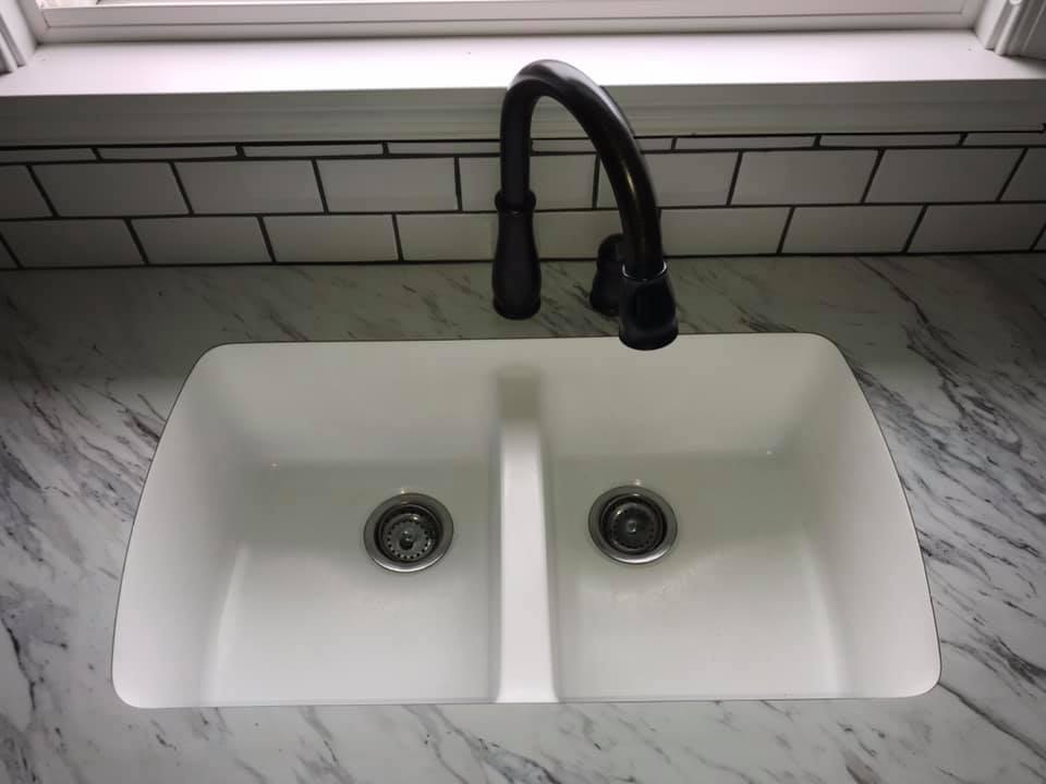 White double kitchen sink with a black faucet.