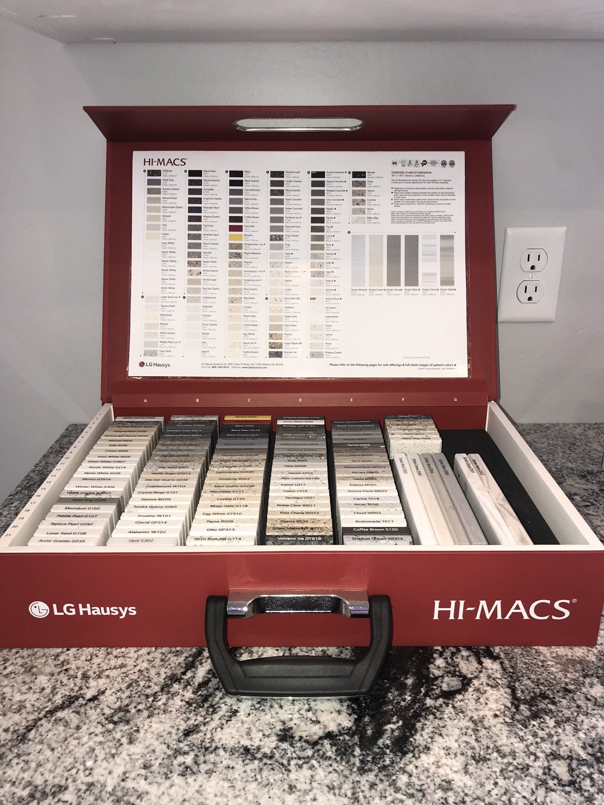 Red HI-MACS sample case open on a countertop, displaying various solid surface material colors and swatches.