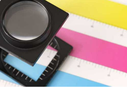 A magnifying glass is sitting on top of a colorful ruler
