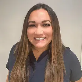 A woman in a blue scrub top is smiling for the camera.