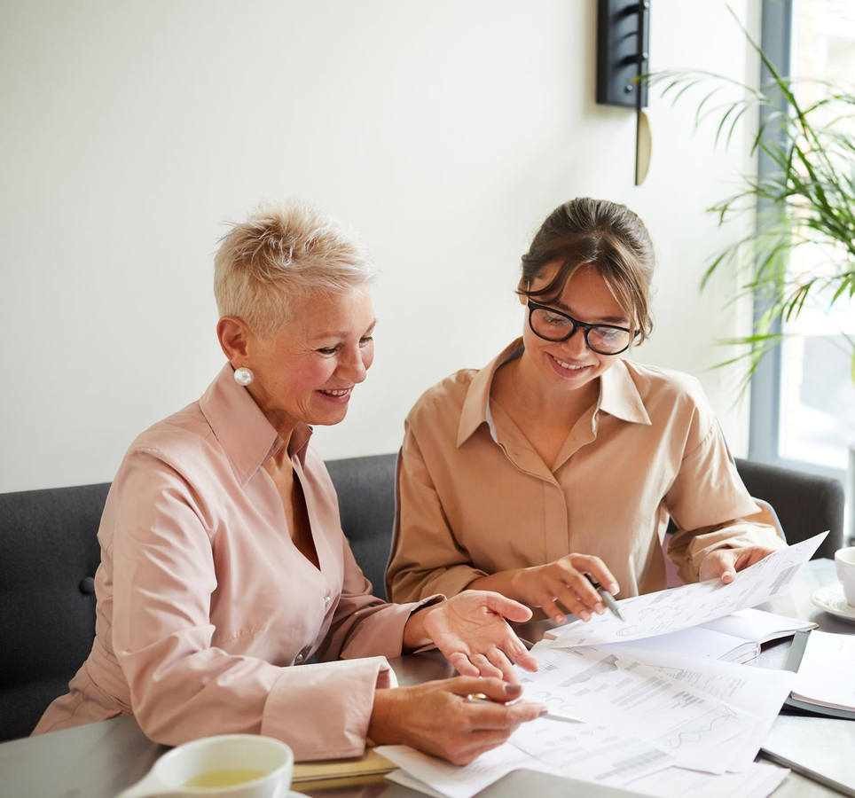 Two people reviewing papers together at a bright office table