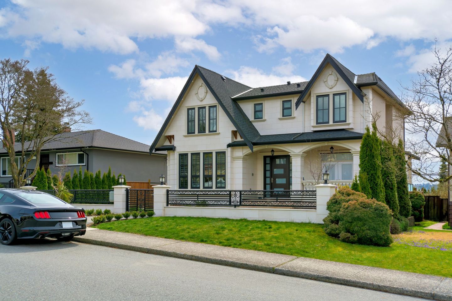 Suburban two-story cream house with a front lawn and parked black car on a quiet street
