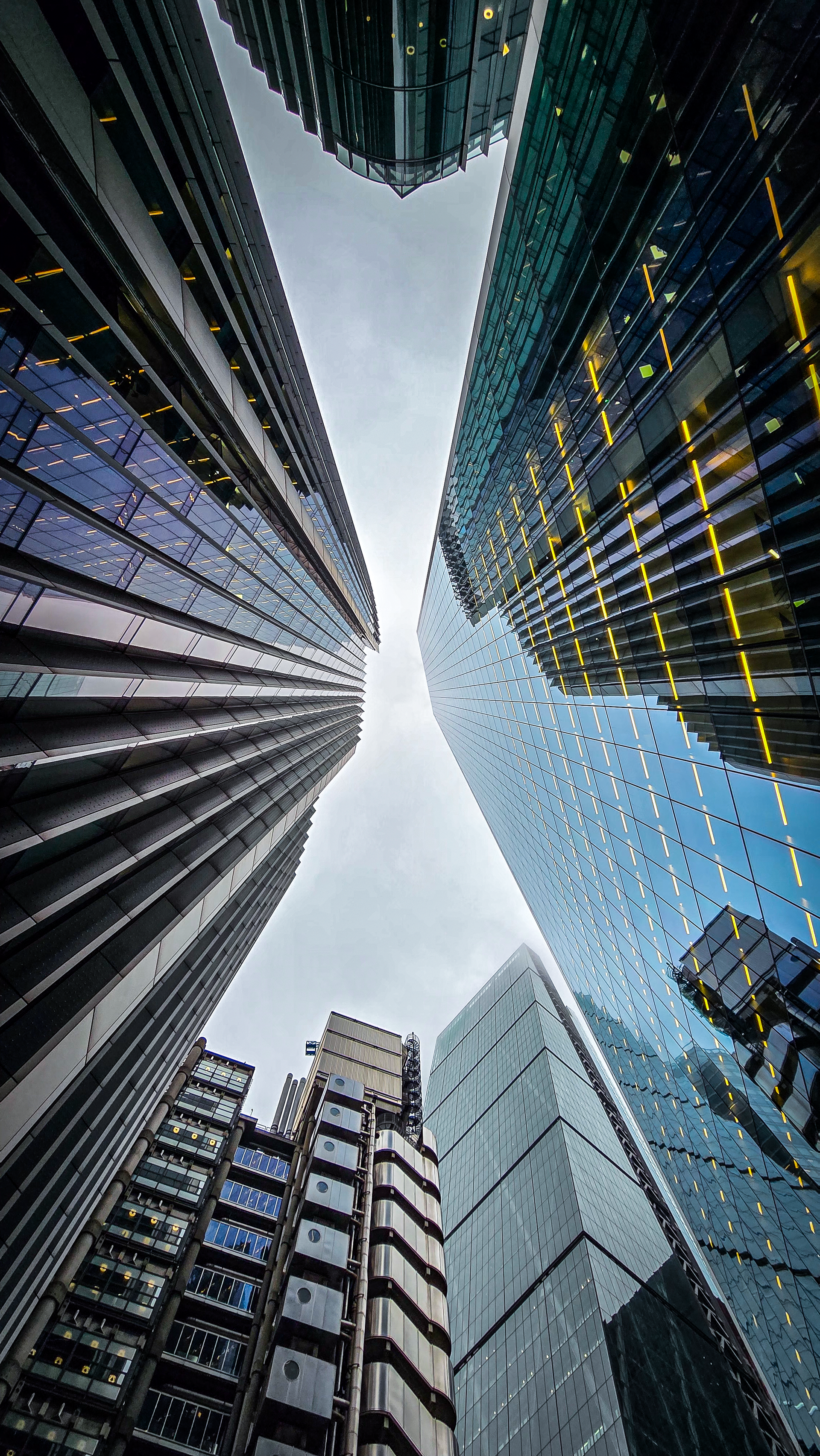 Looking up between tall modern skyscrapers against a bright sky