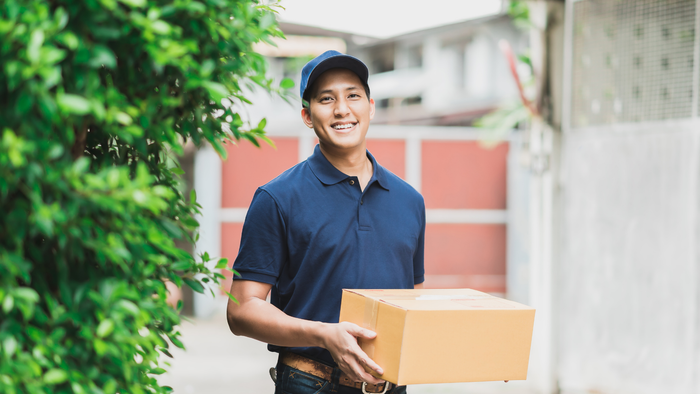 A delivery man is delivering a box to a woman.