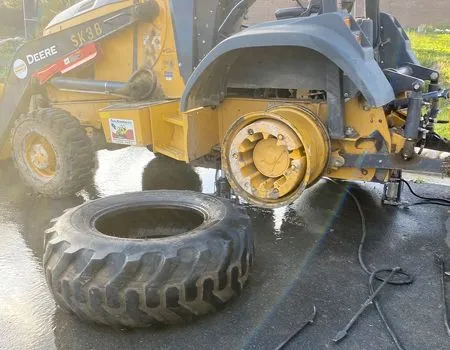 A tractor with a tire on the ground next to it.