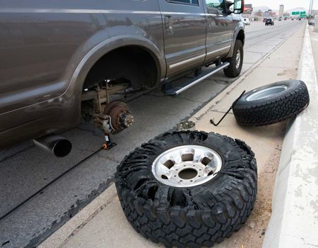 A truck with a flat tire on the side of the road