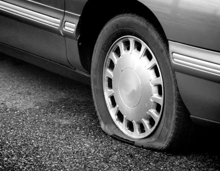 A black and white photo of a car with a flat tire