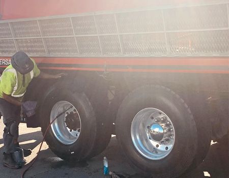 A man is working on the tires of a dump truck.