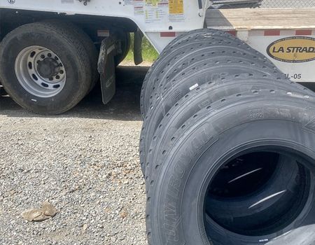 A bunch of tires are stacked on top of each other in front of a trailer.