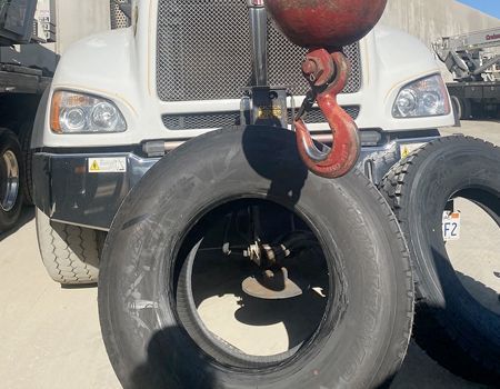 A crane hook is hanging from the front of a truck.