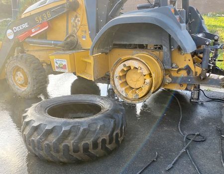 A tractor with a tire on the ground next to it.