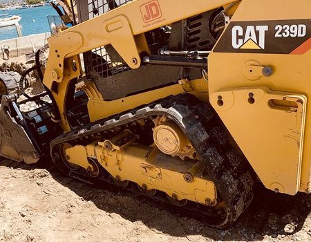 A yellow cat bulldozer is parked in the sand