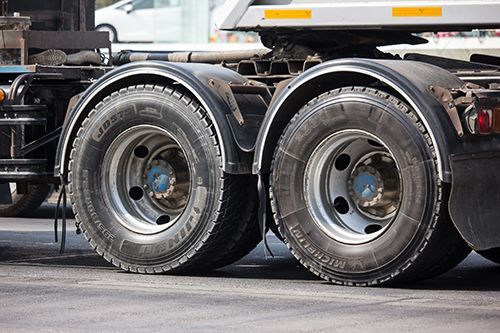 A close up of a semi truck 's tires and fenders