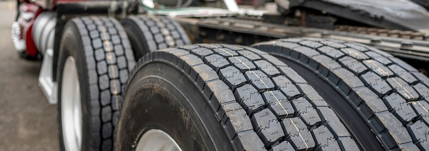 Close-up of truck tires with tread, showing the wheels and the undercarriage of the vehicle.