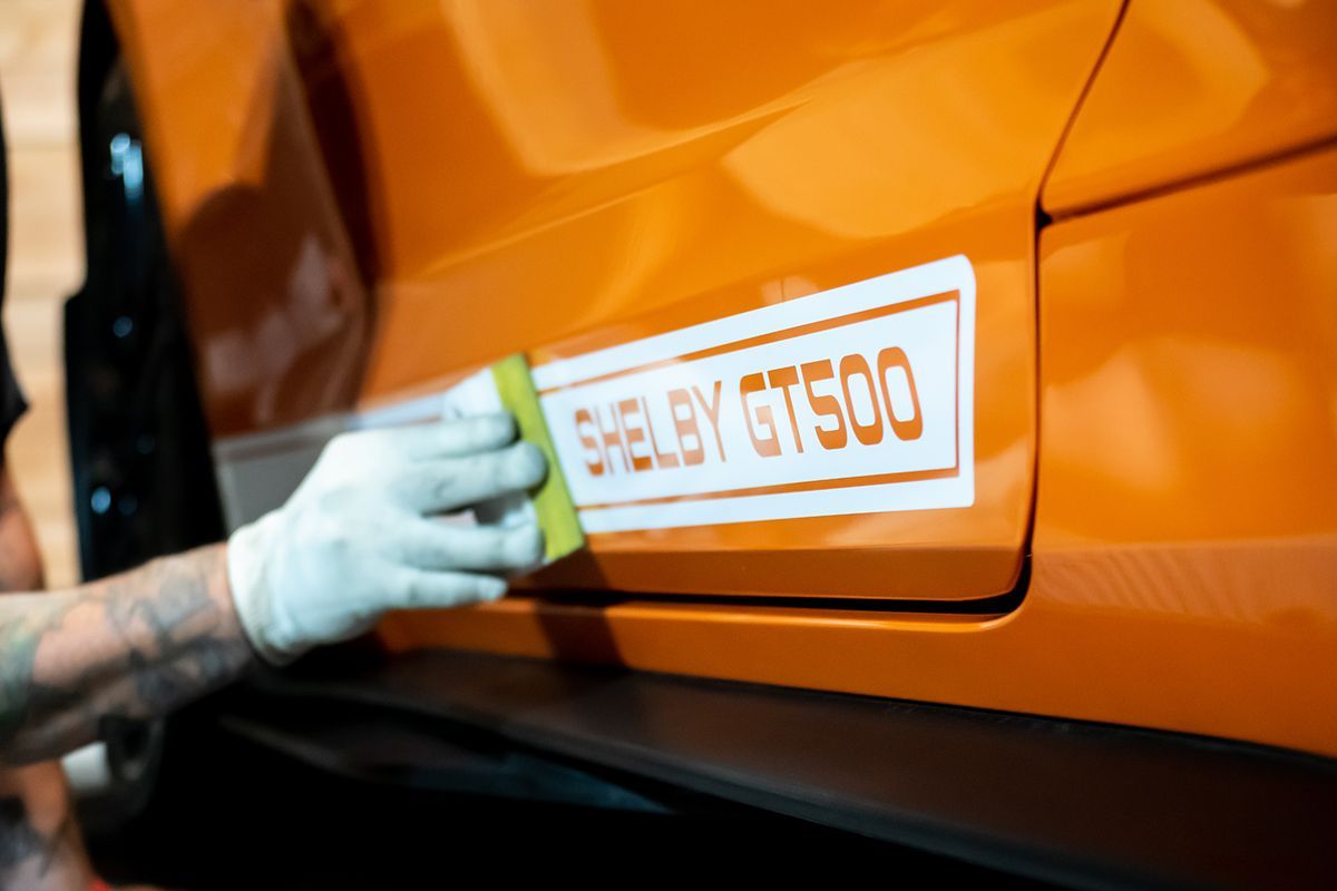 A close up of the side of an orange shelby gt500.