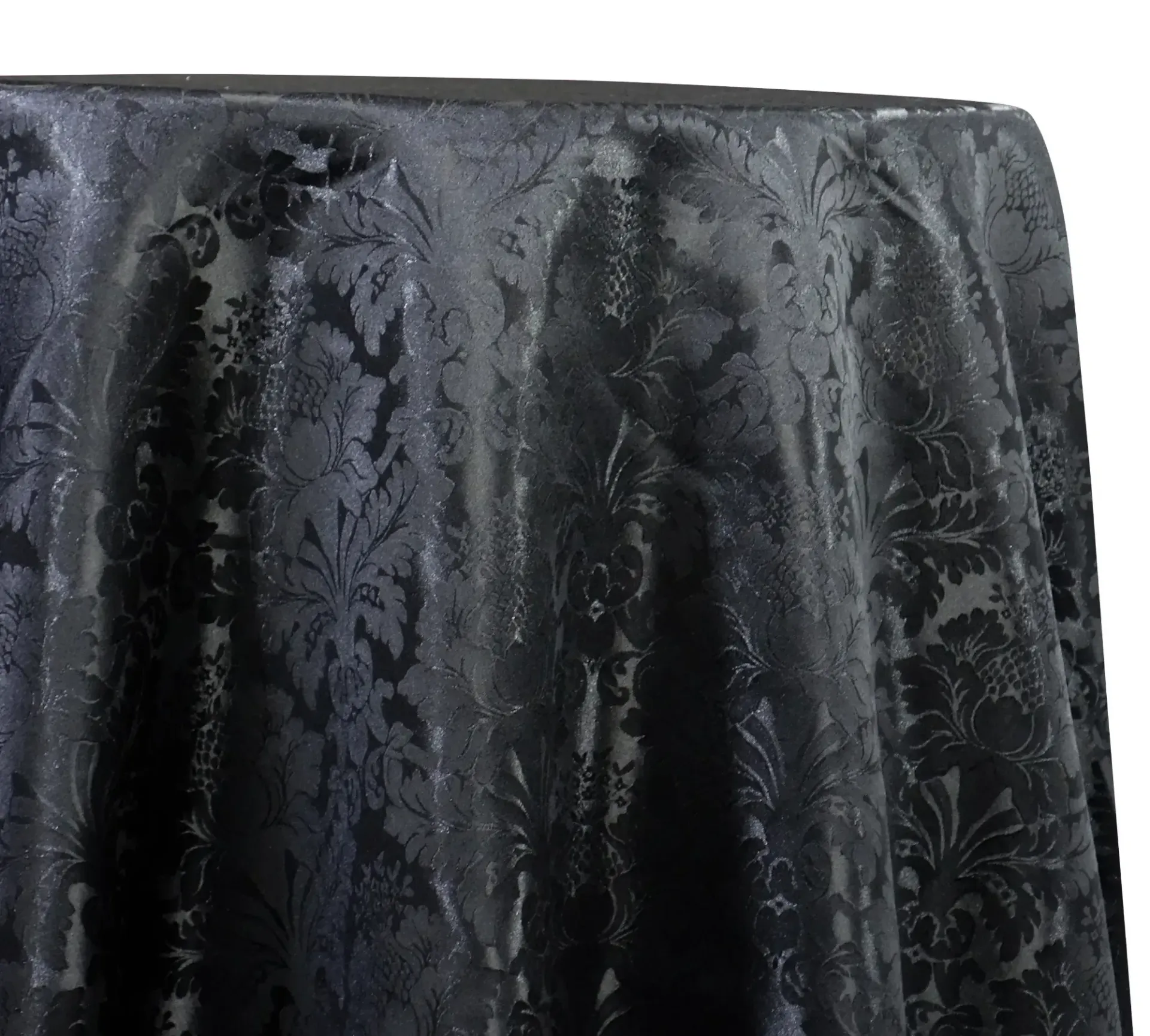 Black patterned fabric draped over a surface, with a subtle floral texture